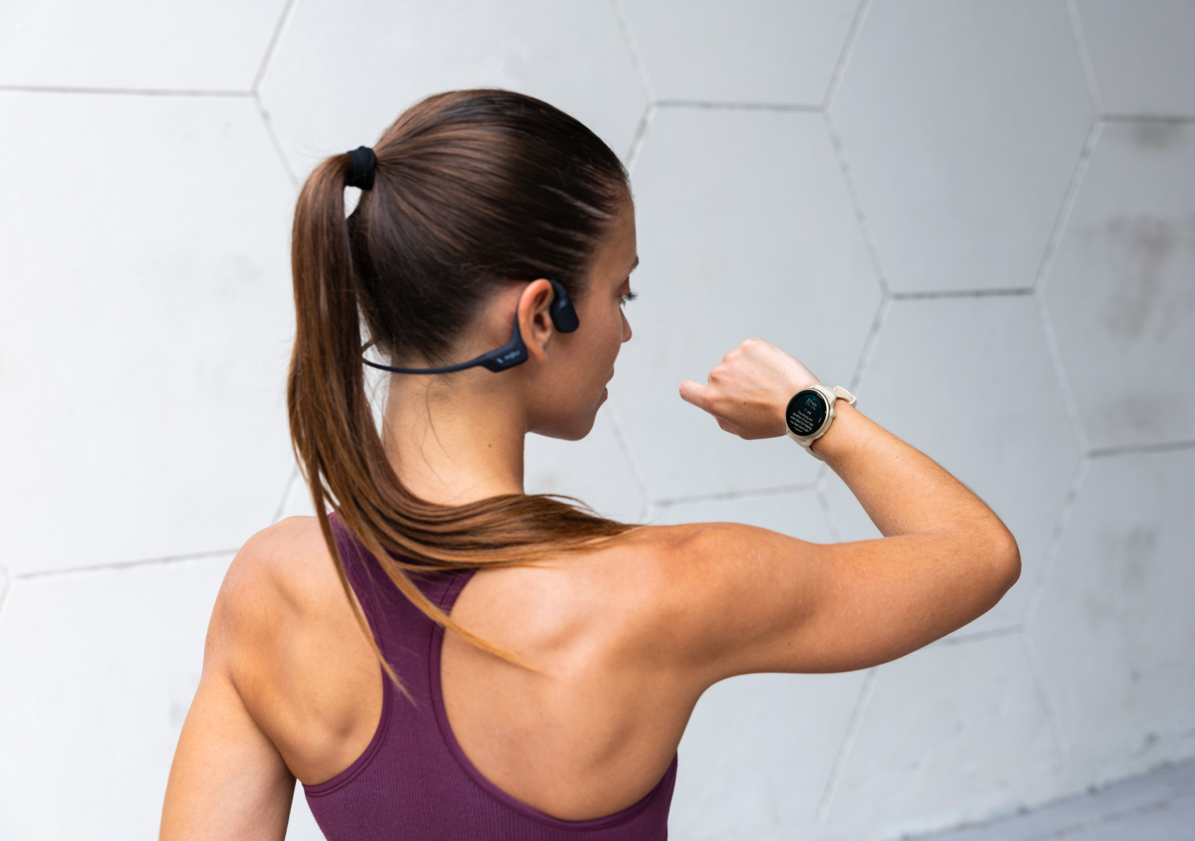 vrouw met shockz kijkt op garmin horloge