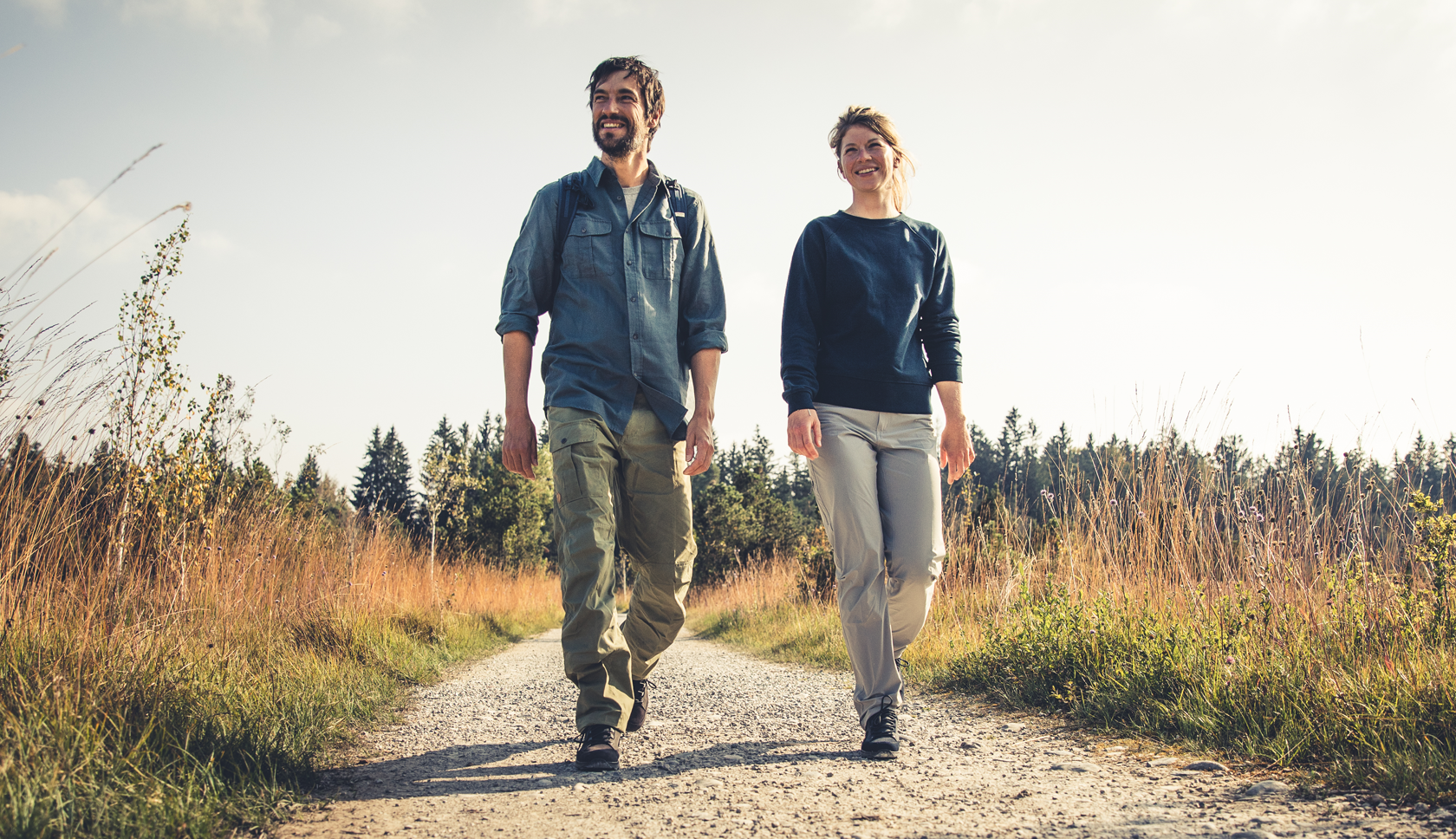 twee mensen wandelen vrolijk over duinpad