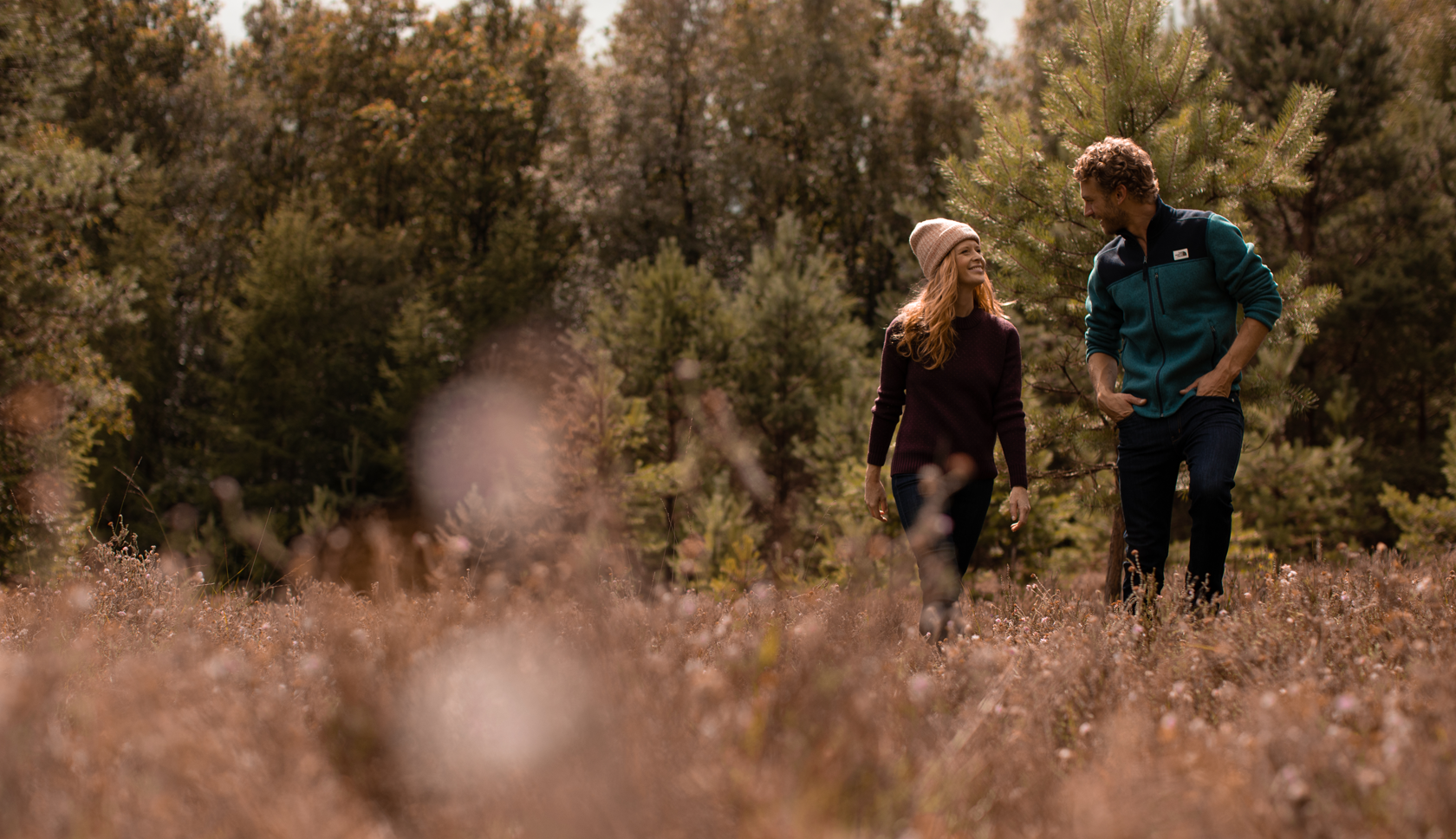 twee mensen praten in het bos, kniediep in heidebloemen