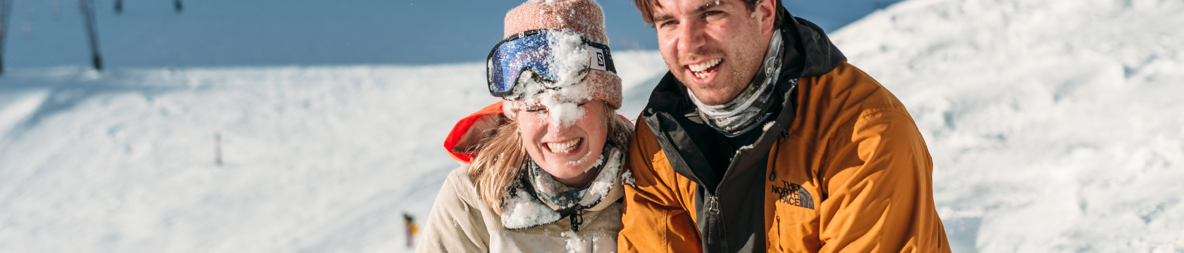 Een man en vrouw lachen in de sneeuw