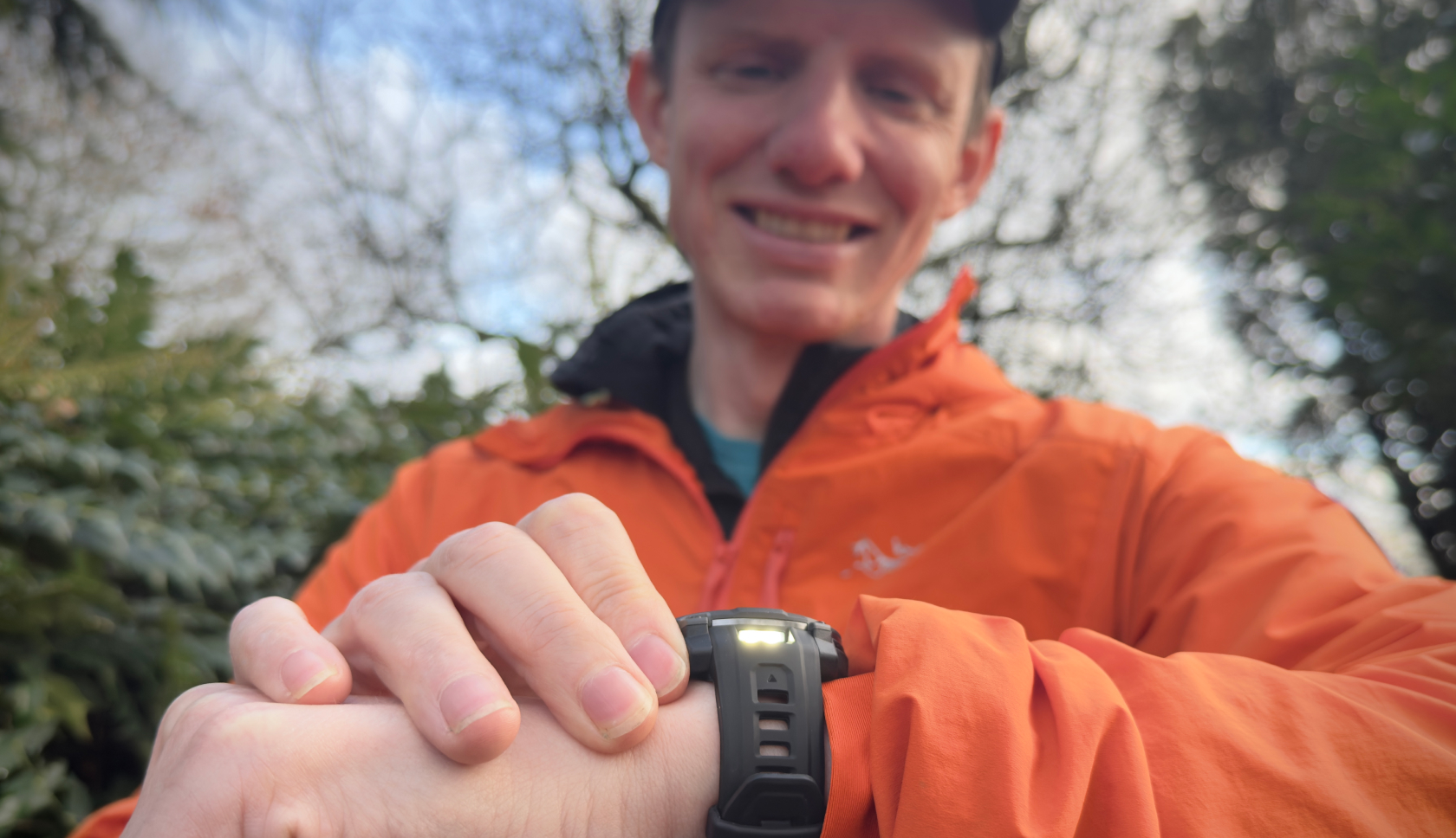 Een man kijkt lachend naar zijn horloge in het bos