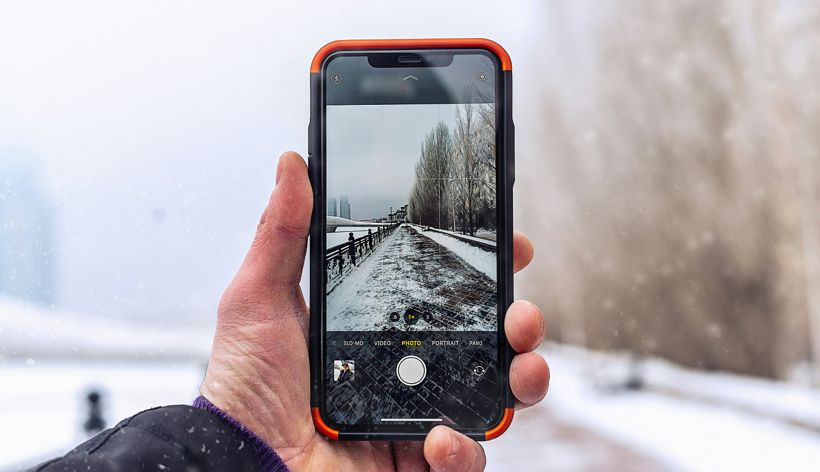 Iemand maakt met een iphone een foto van een besneeuwd landschap 