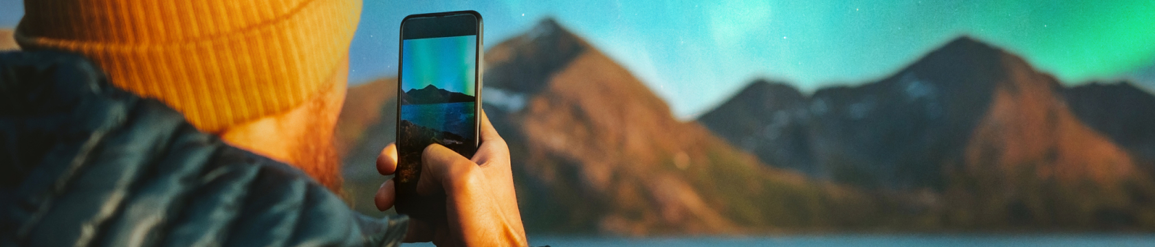 Een man maakt foto's met zijn telefoon van noorderlicht