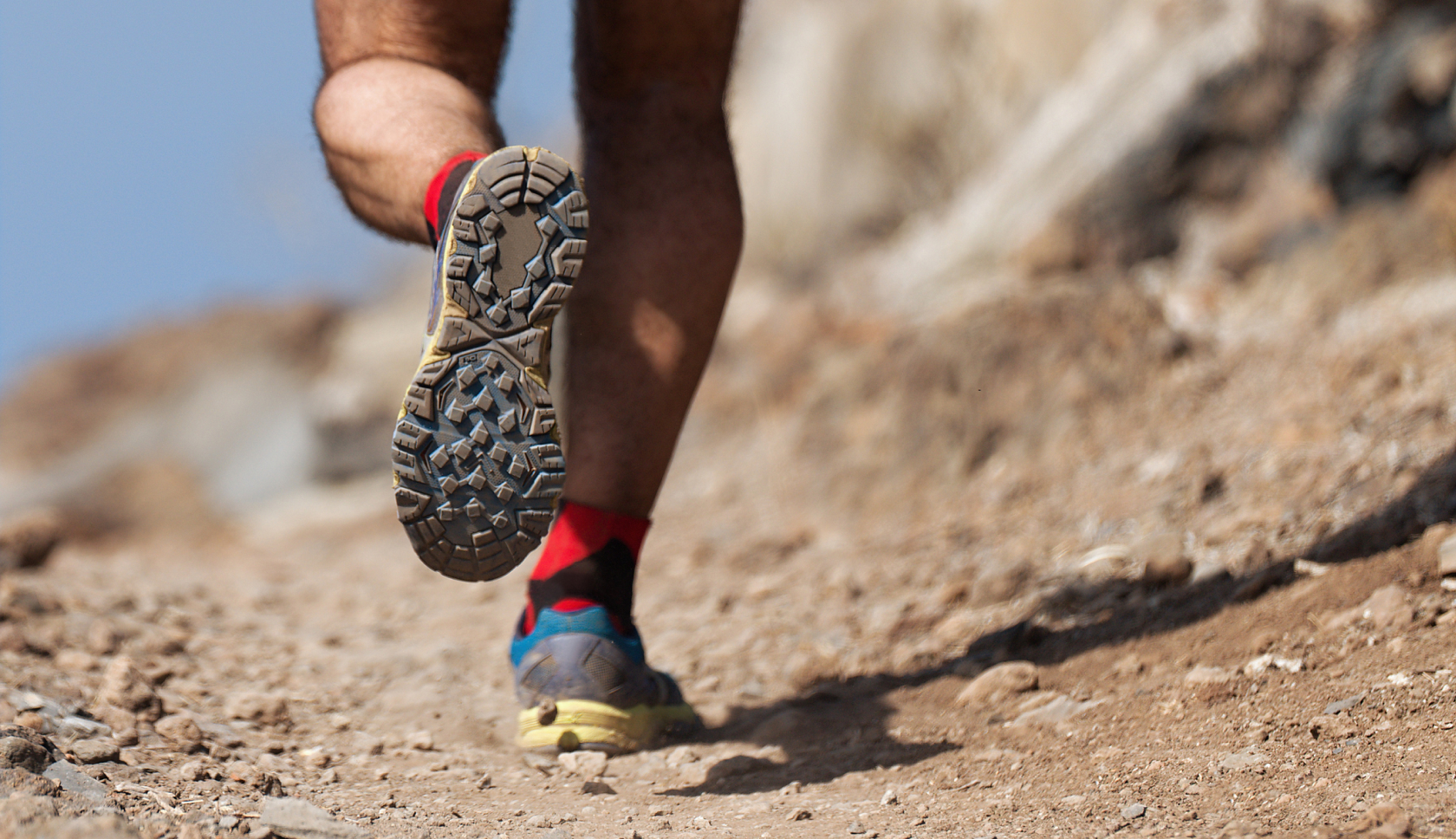 close up trailrunschoenen over rotsachtig terrein