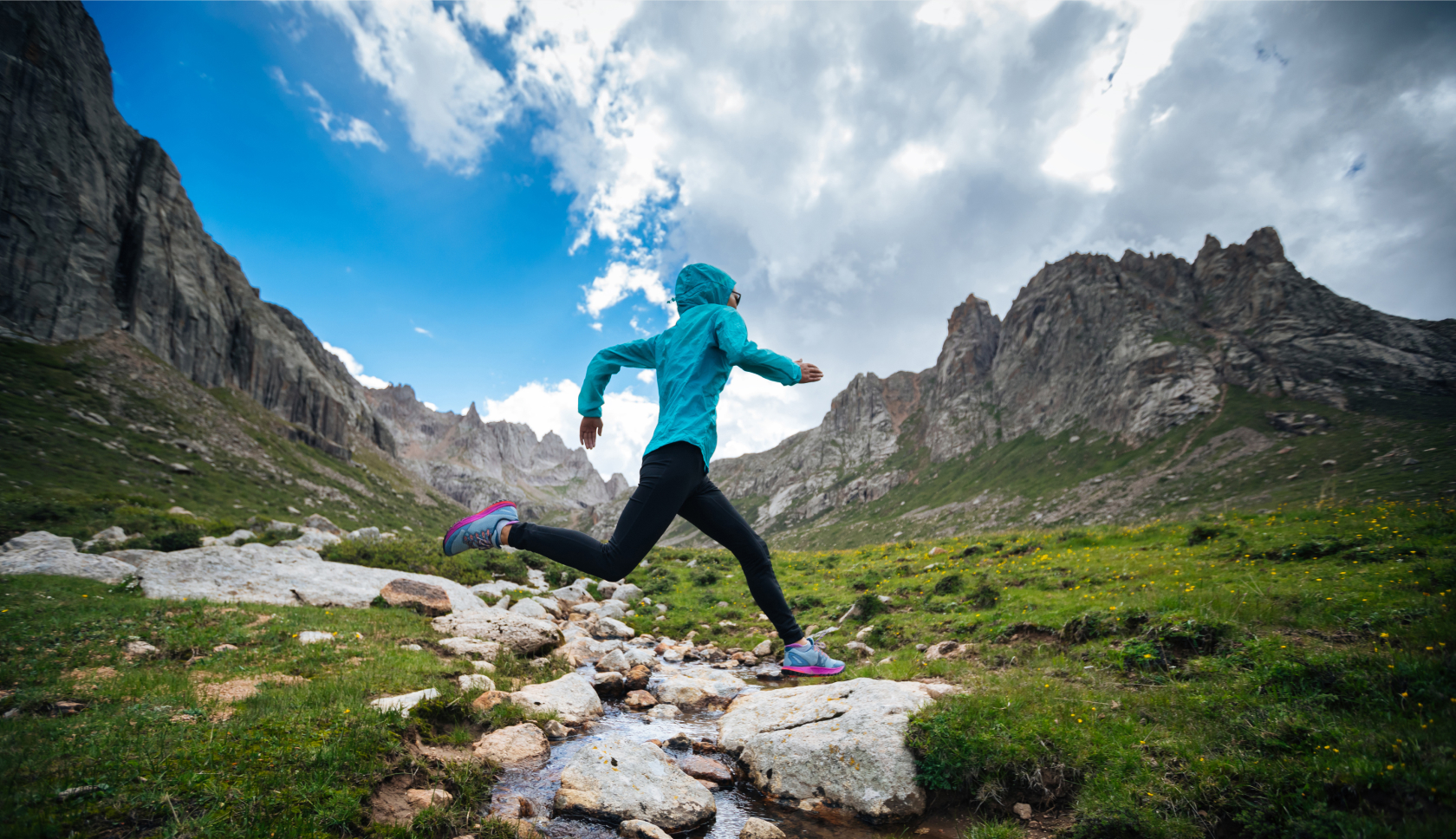 vrouw springt over beekje tijdens trailrun in dal