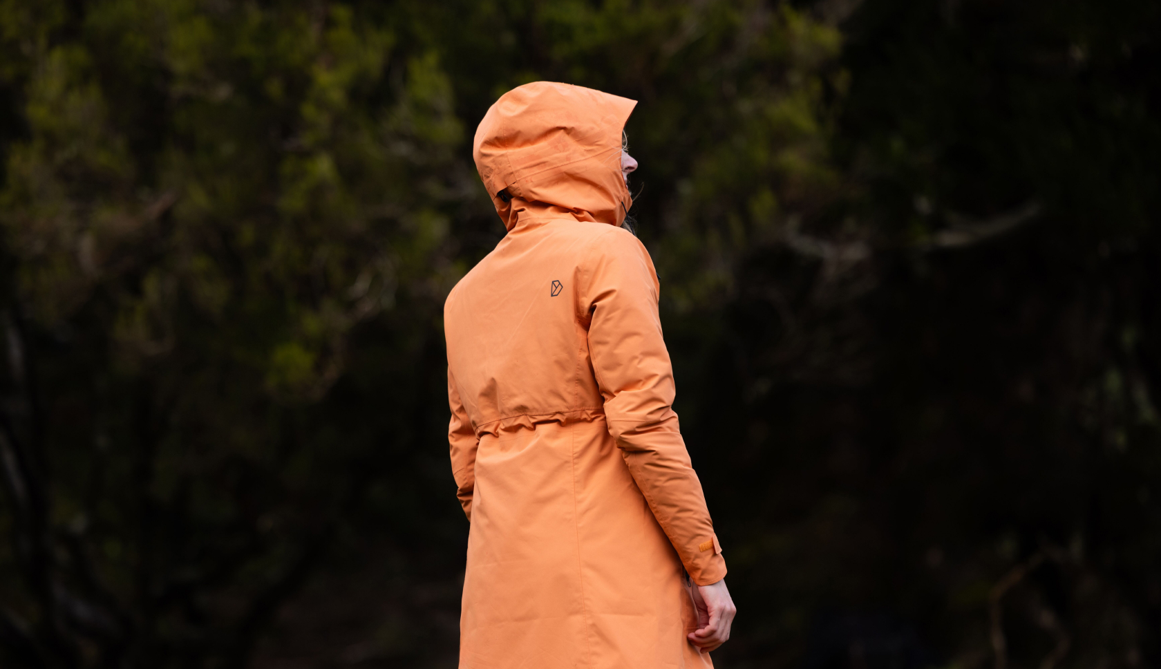 vrouw met haar rug naar de camera in oranje jas
