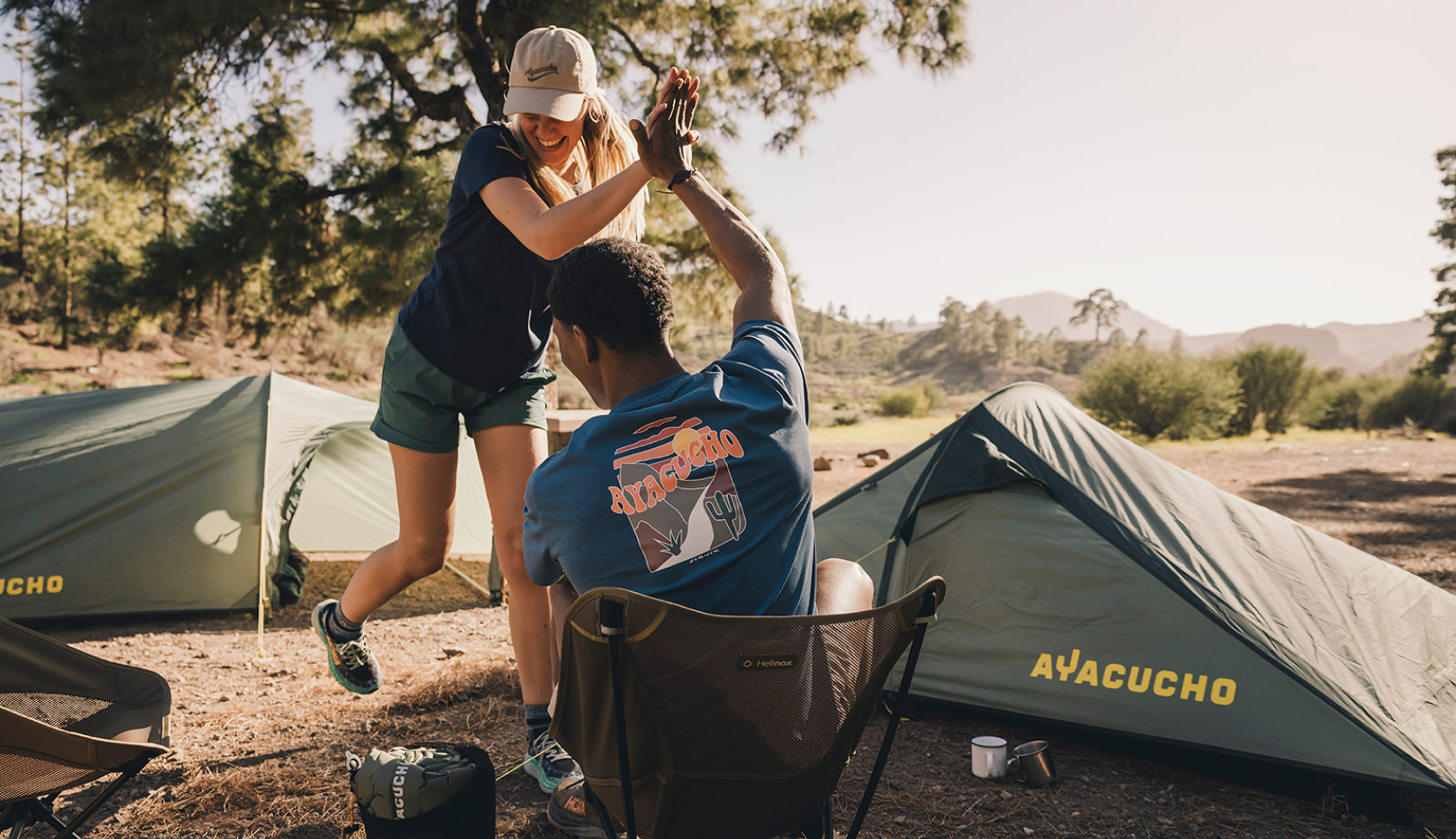 Een man op een campingstoel geeft een high five aan een vrouw die voor hem staat
