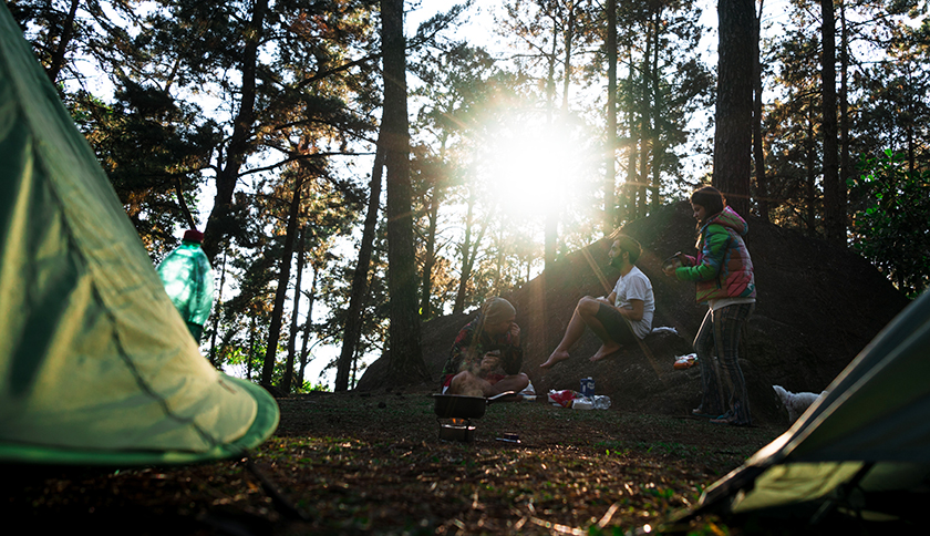 mensen zitten bij hun tent in het bos
