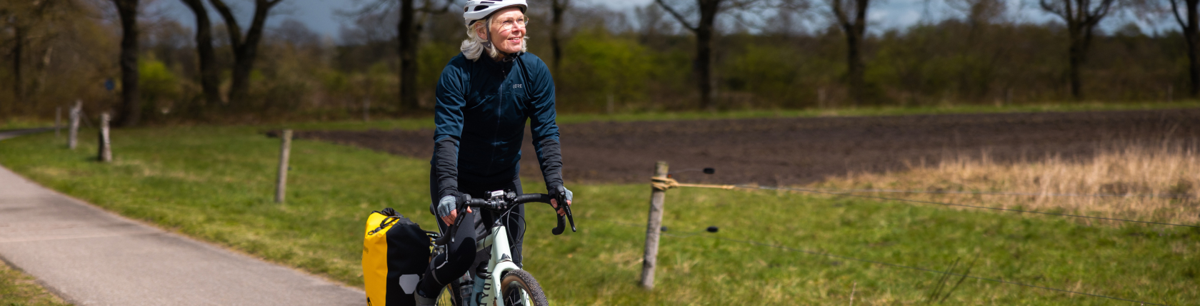 Een vrouw fietst door een polderlandschap