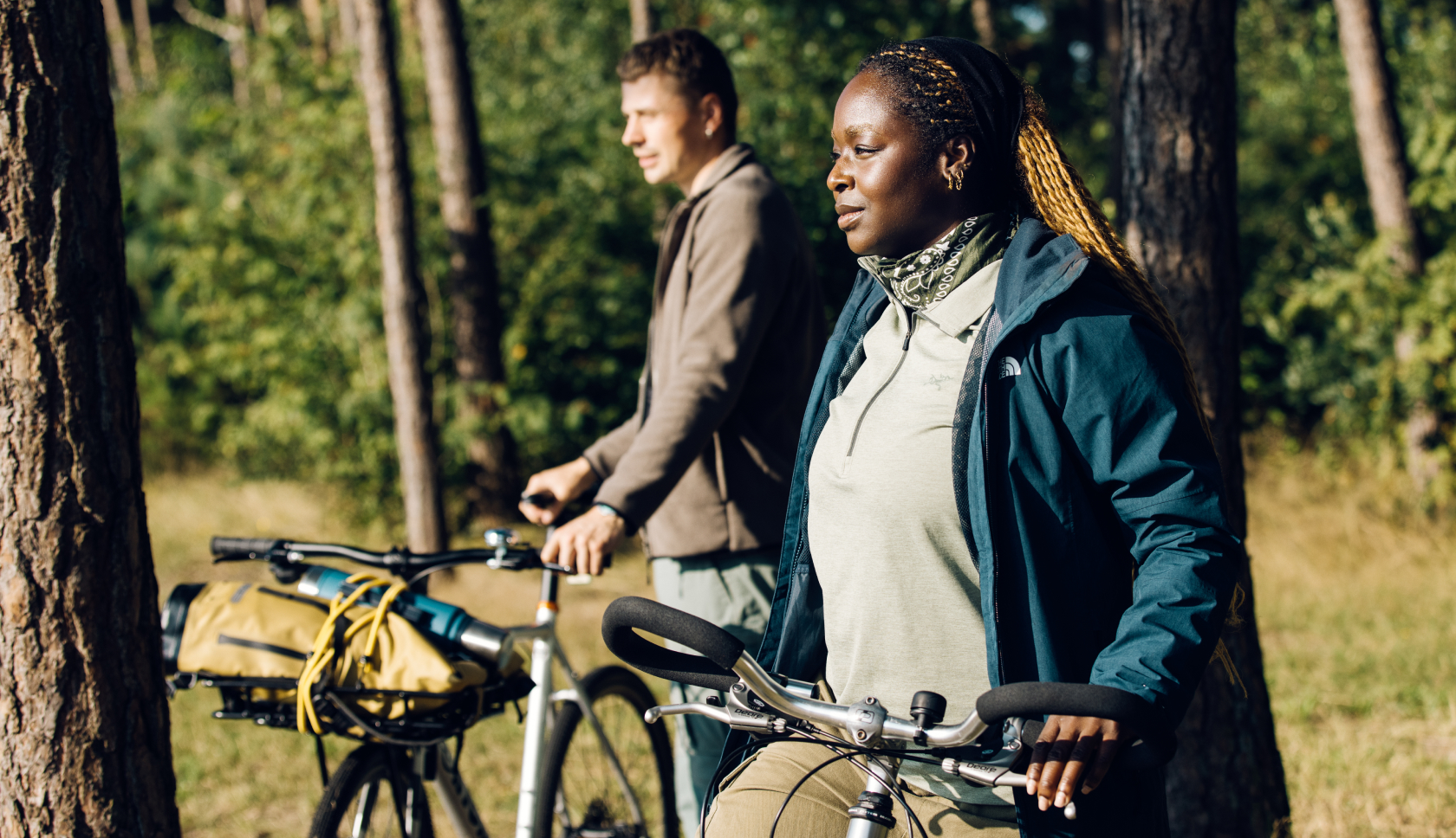 Twee mensen staan met de fiets in de hand in een bos