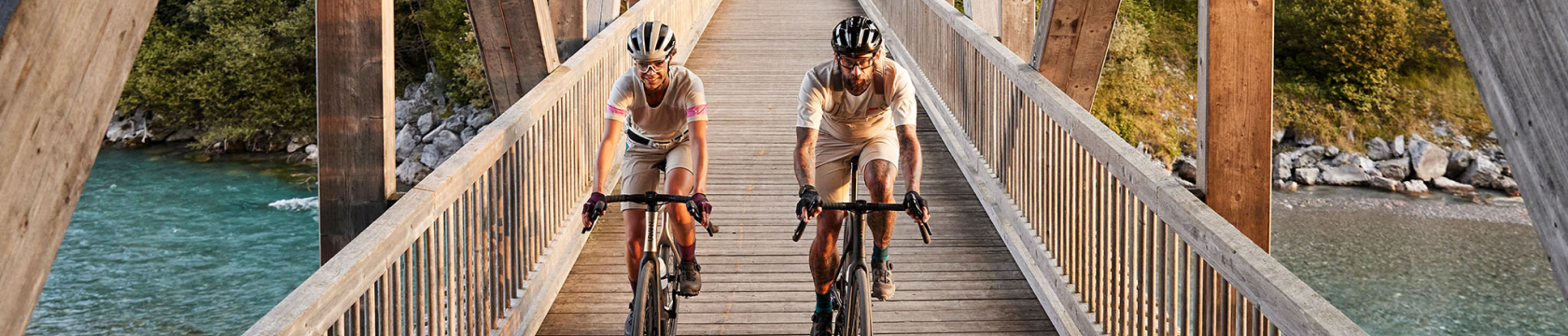 Twee personen fietsen over een houten brug.