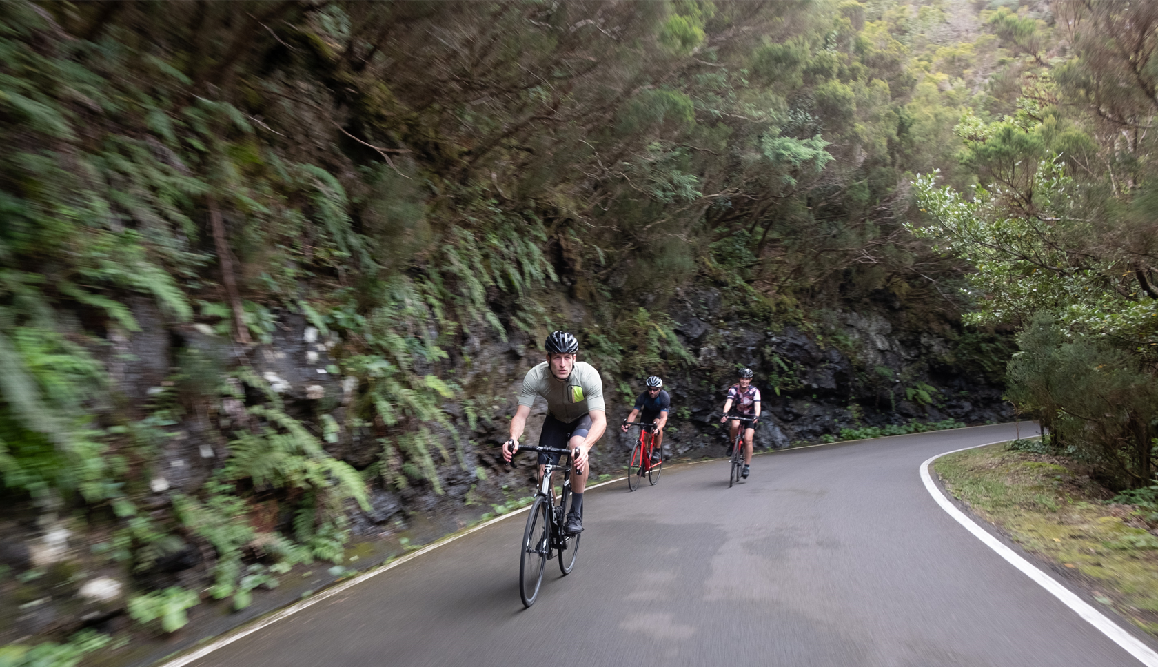 drie racefietsers fietsen heuvel af