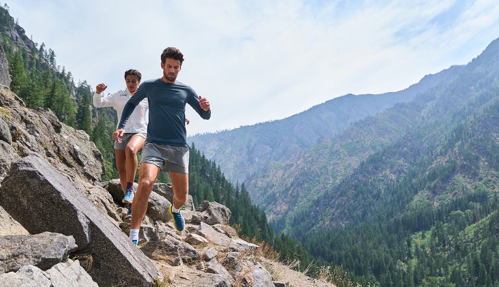 man en vrouw trailrunnen over stenen pad in bergen