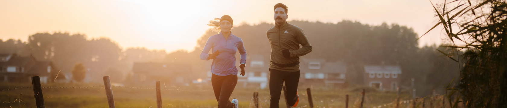 Een man en een vrouw lopen hard bij zonsondergang