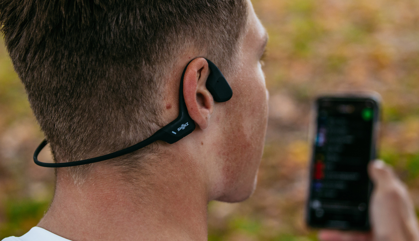 Een man luistert naar muziek via een draadloze koptelefoon van shokz