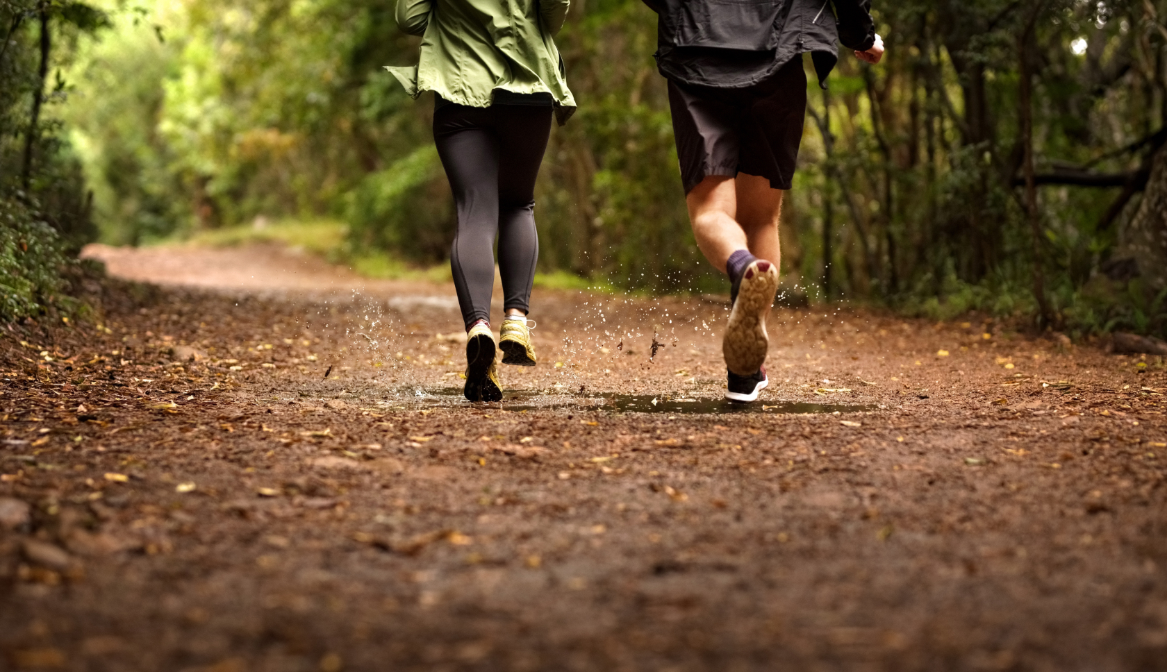 Twee mensen trailrunnen op een bospad