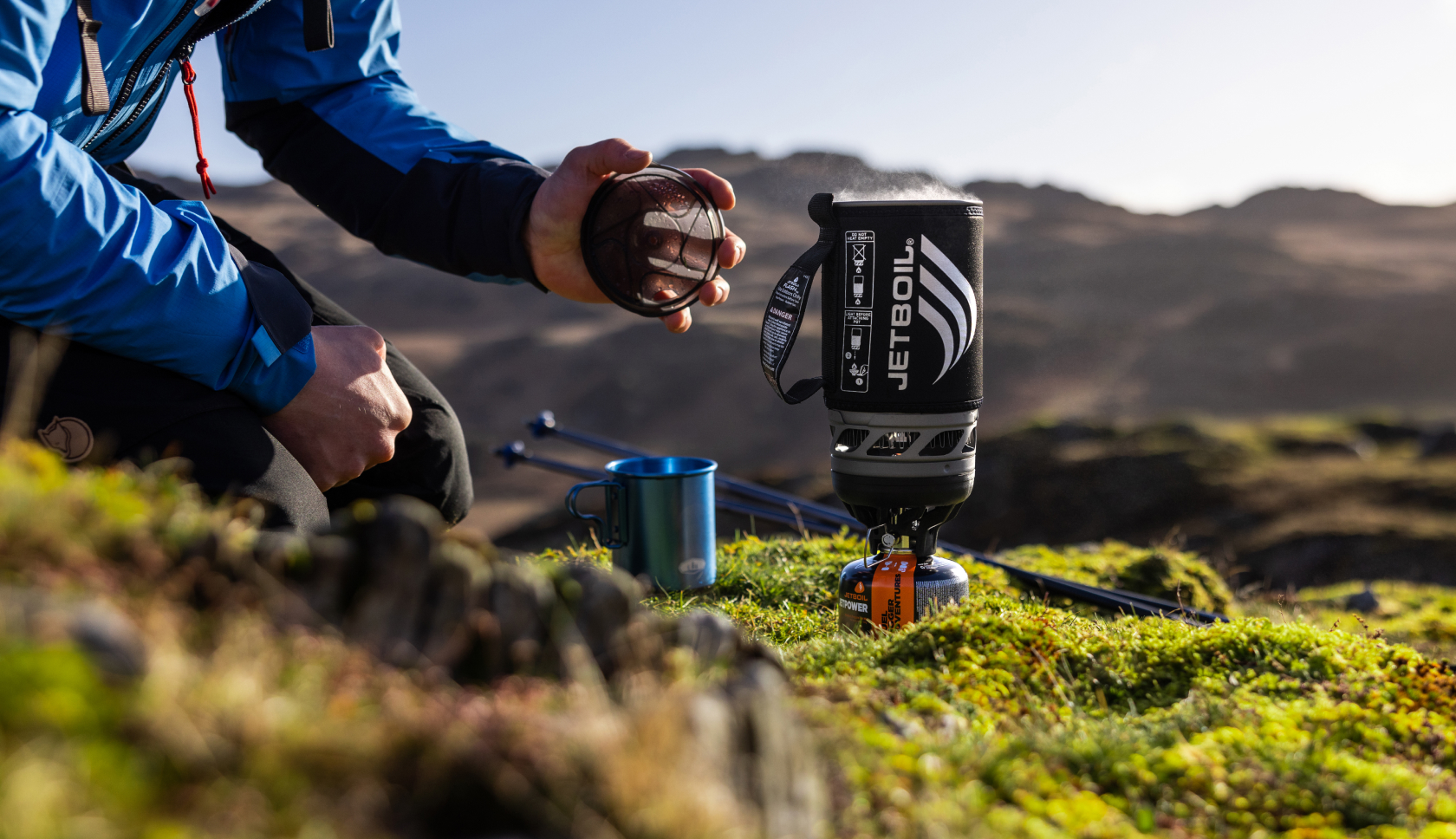 Een jetboil met kokend water staat op een ondergrond van mos