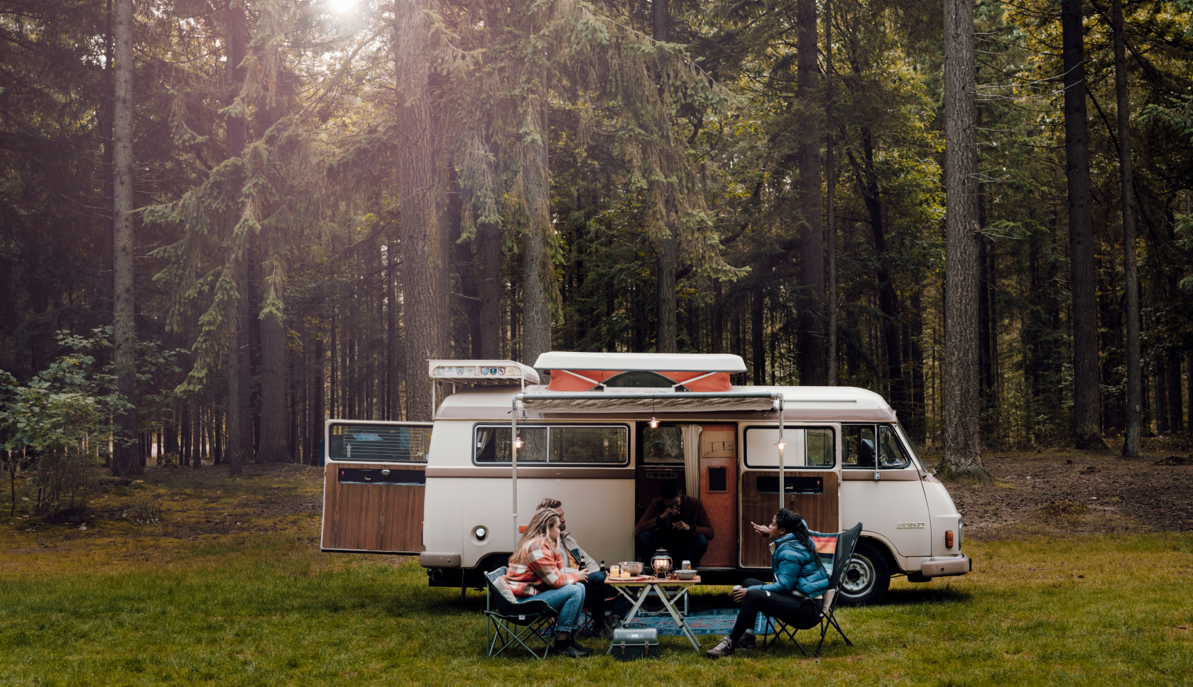 Mensen zitten voor een campervan te eten.