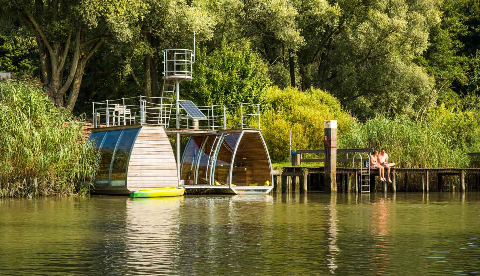 Een ecolodge drijft op het water tussen de bomen.
