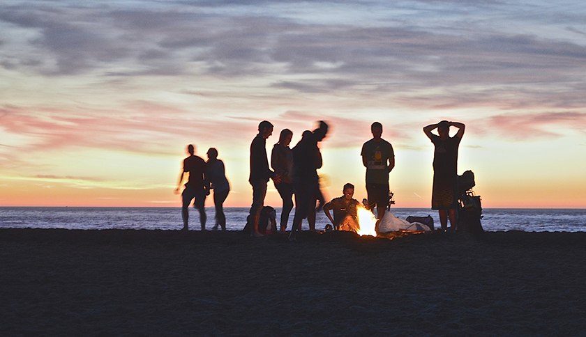 groep mensen om kampvuur op het strand