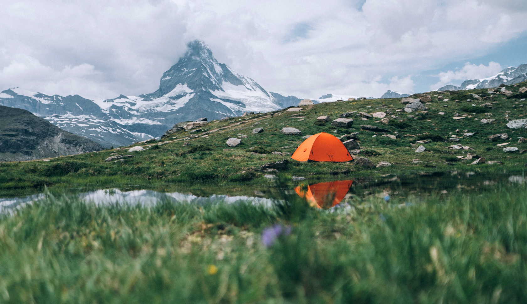 Een tent staat bij een bergmeer in Zwitserland, op de achtergrond prijkt de Matterhorn