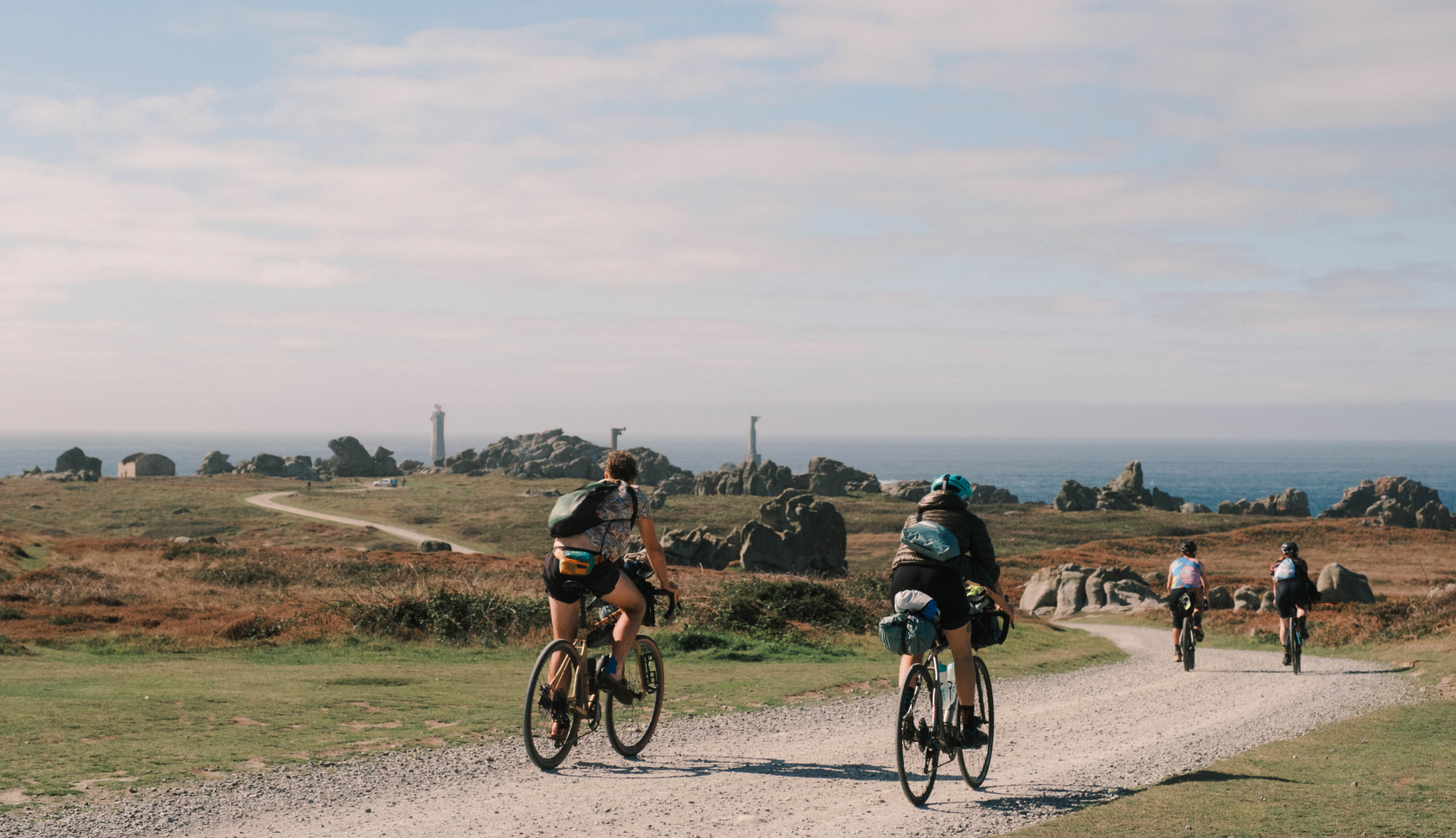 Een aantal mensen fietsen over een grindweg richting de zee