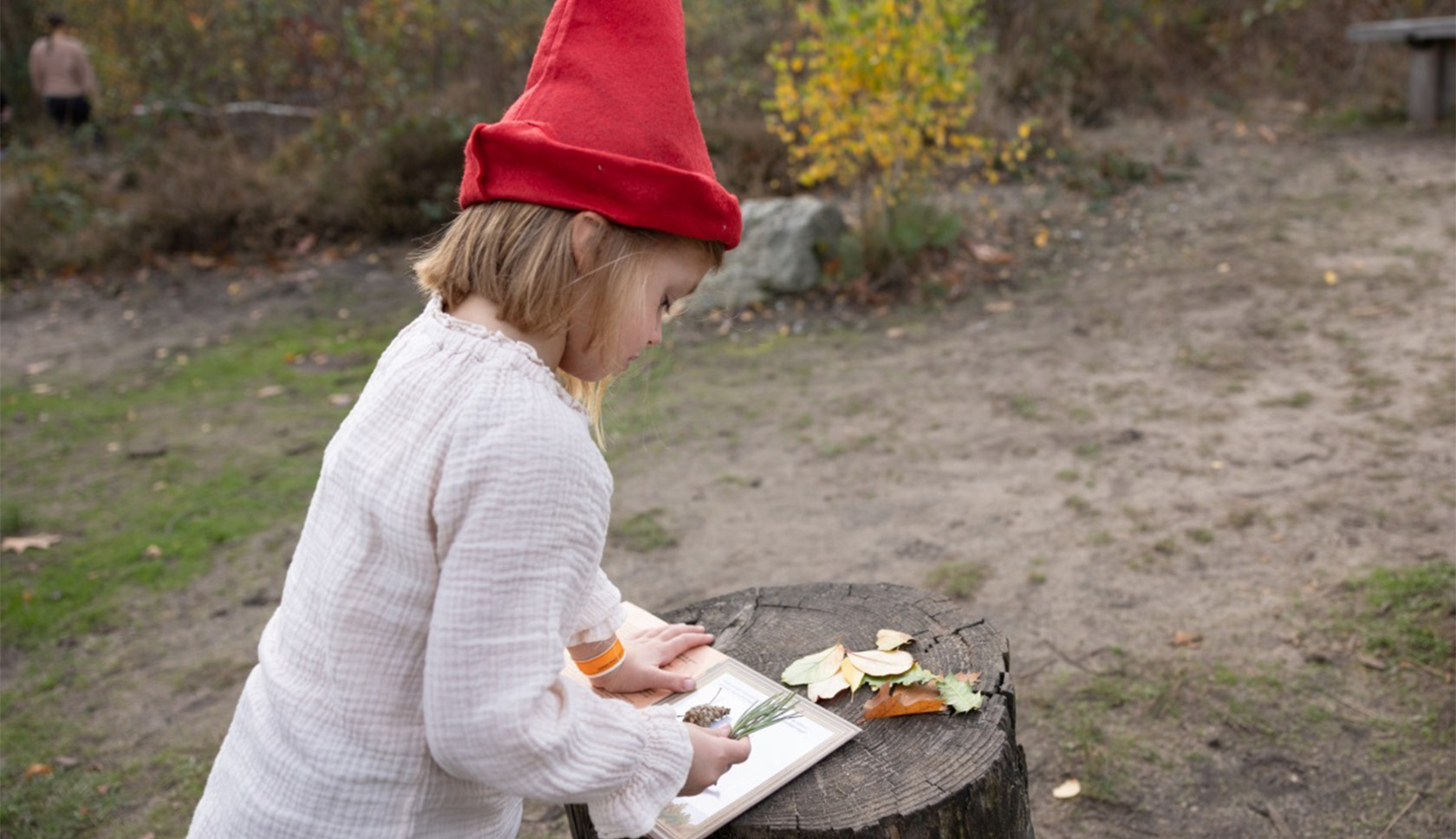 meisje met een kaboutermuts op leest een boekje in het bos