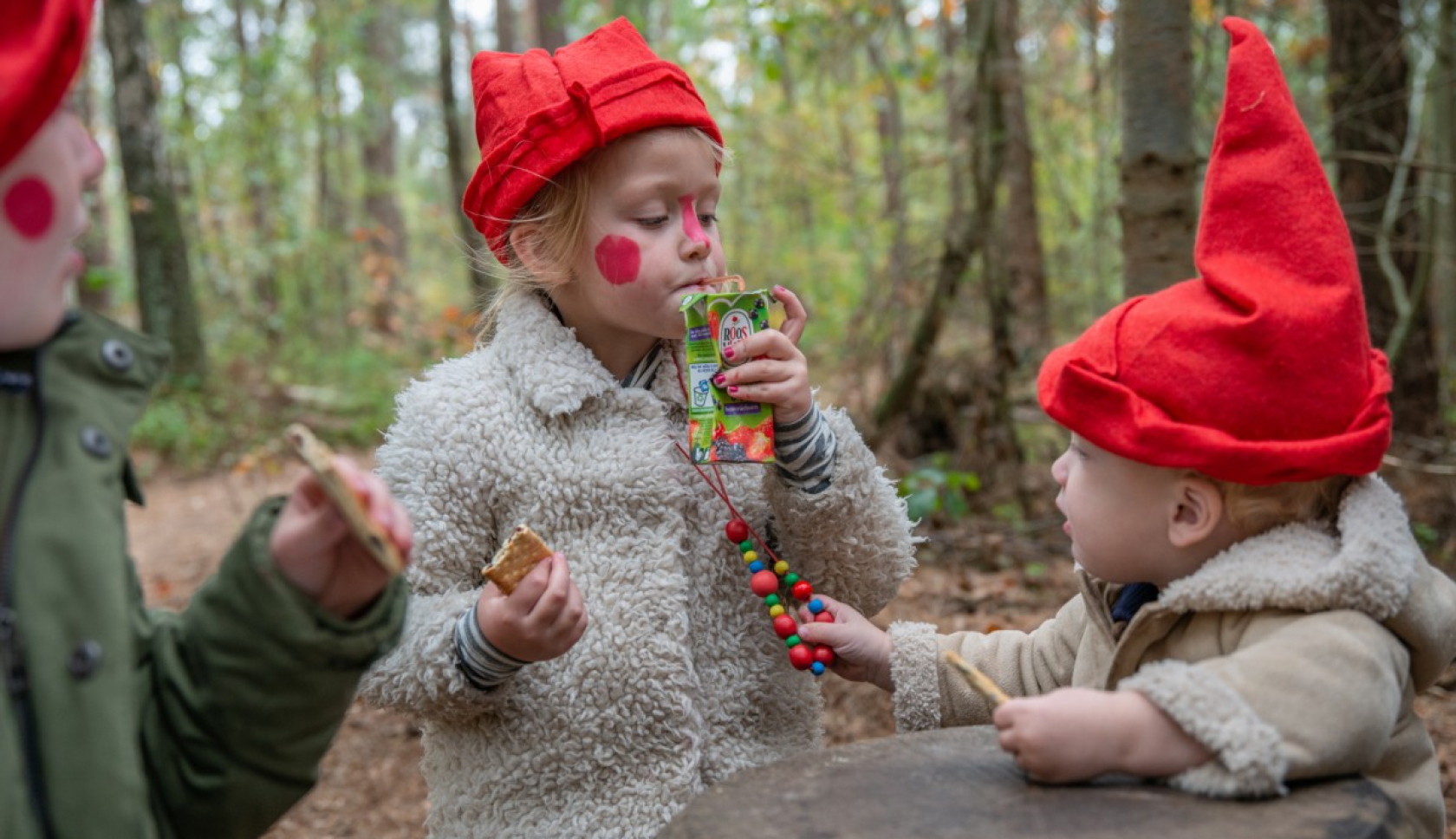 Kind met kaboutermuts leest een opdrachtkaartje tijdens een kabouterwandeling