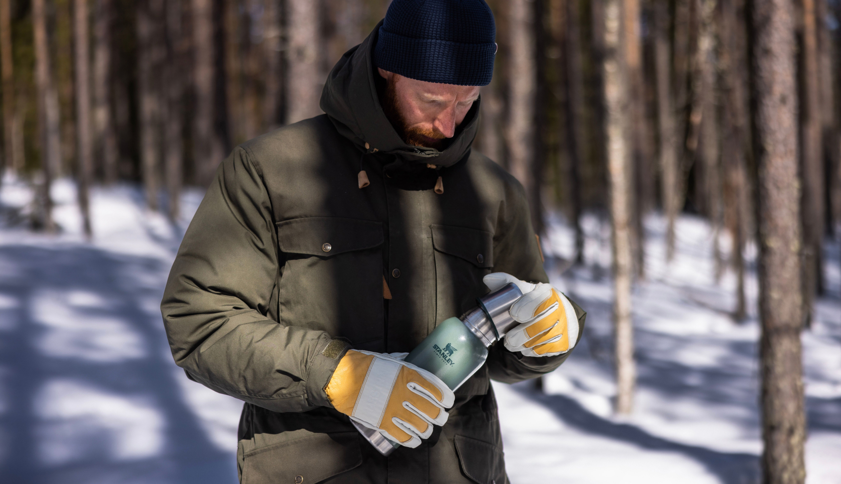 man met thermosfles wandelt door besneeuwd bos
