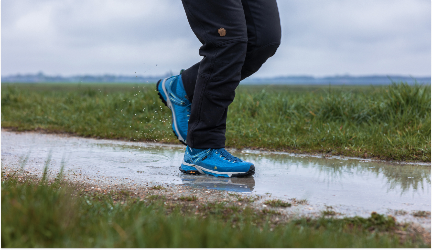 Blauwe meindelschoenen stappen door plas op de weg 