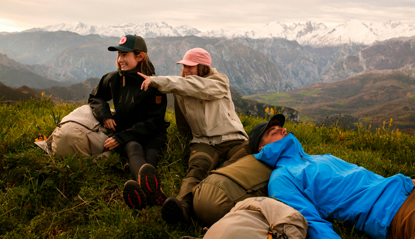 Drie wandelaars in fjallraven-kleding rusten uit in het gras