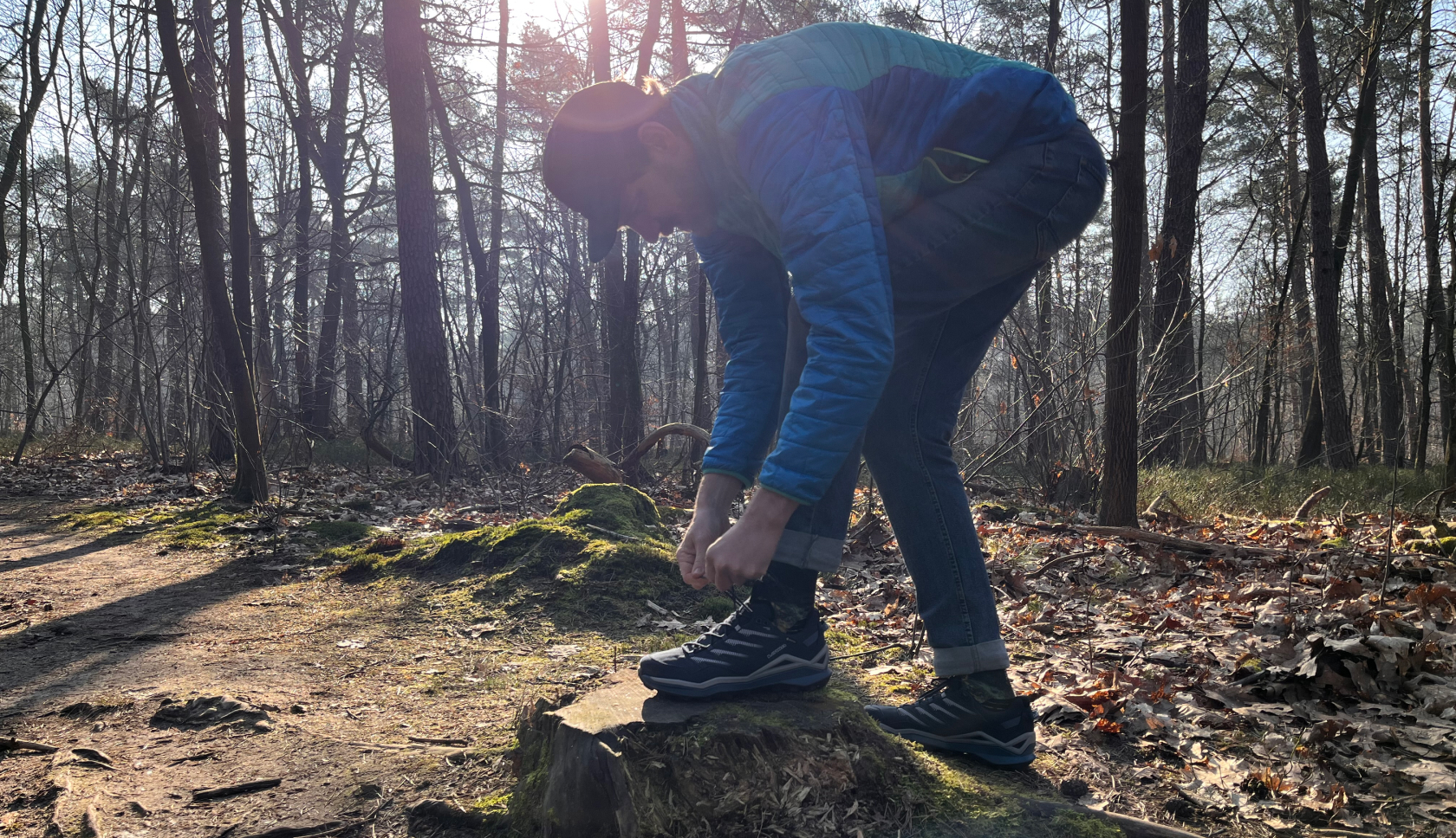 Een man staat in het bos en lust zijn schoenveters