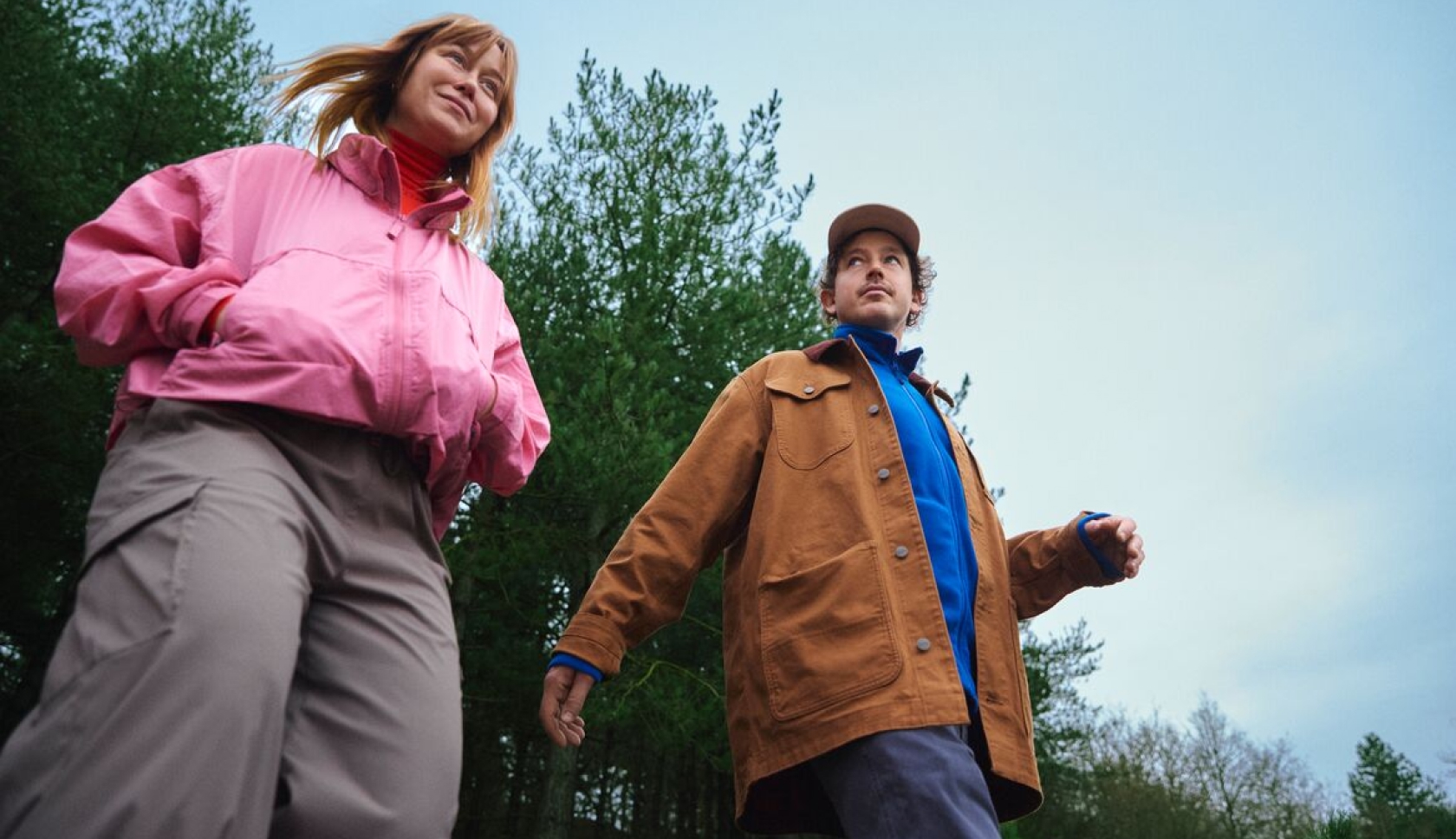 Vrouw in een kleurrijke fleecetrui geniet van de buitenlucht in een bos.