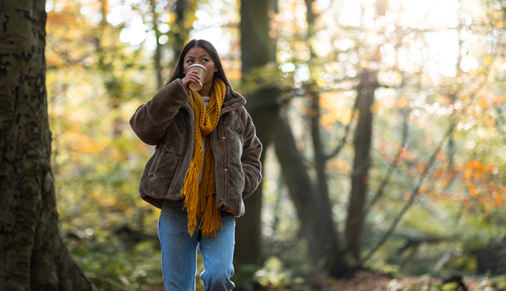 Vrouw drinkt koffie tijdens een wandeling in een herfstachtig bos