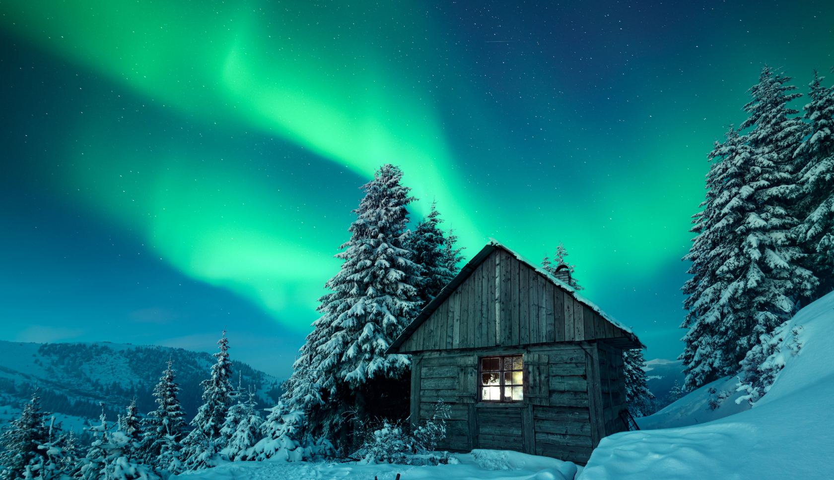 Besneeuwd houten huisje steekt af tegen het felle, groene noorderlicht.