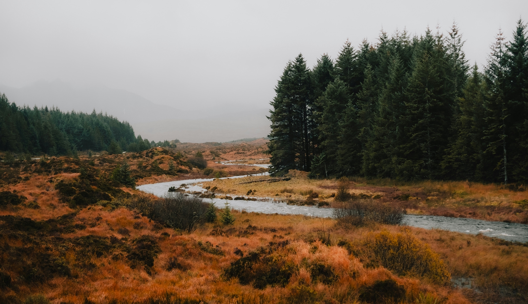 Twee personen staan in regenkleding op een bergtop.
