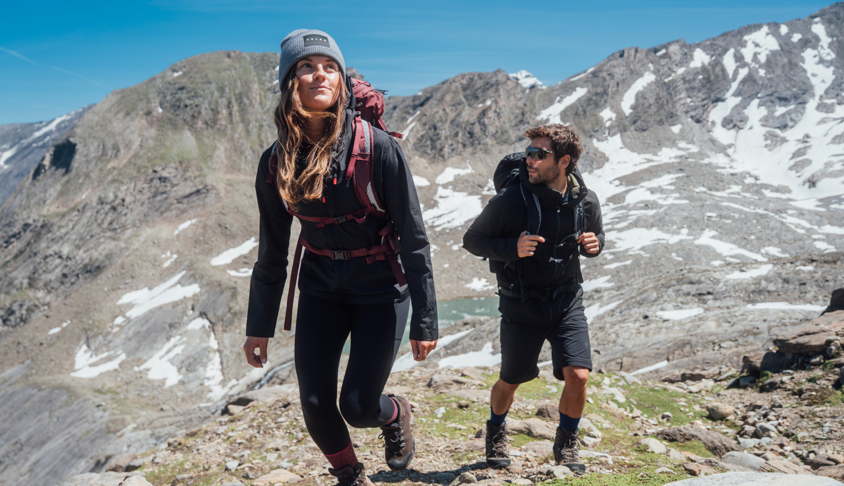 Twee mensen wandelen door de bergen met rugzakken om.