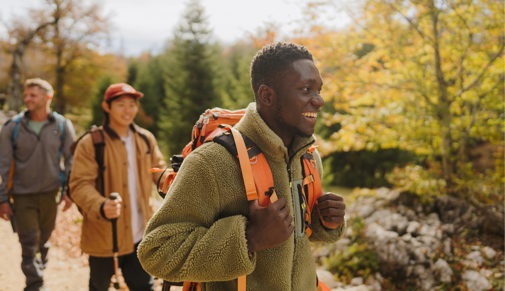 Drie wandelaars in warme kleding tijdens een herfstwandeling door het bos.