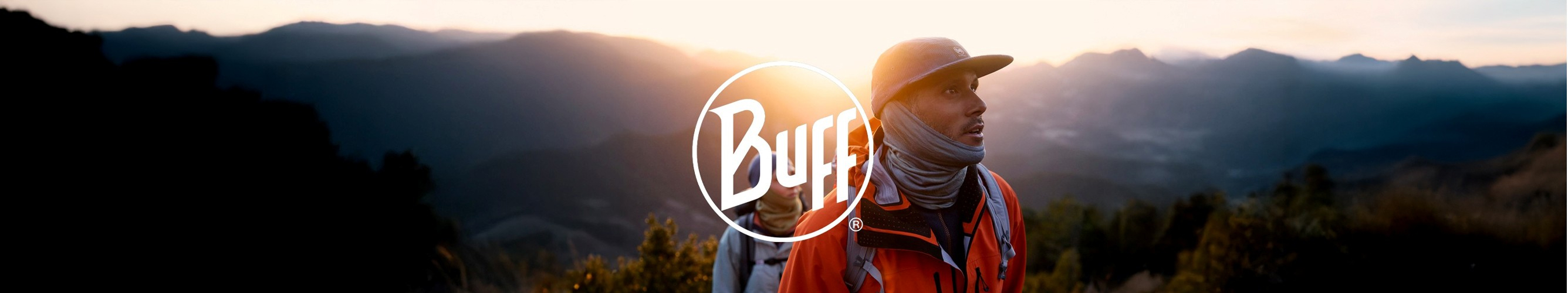 man met pet en buff wandelt in de bergen bij zonsopgang