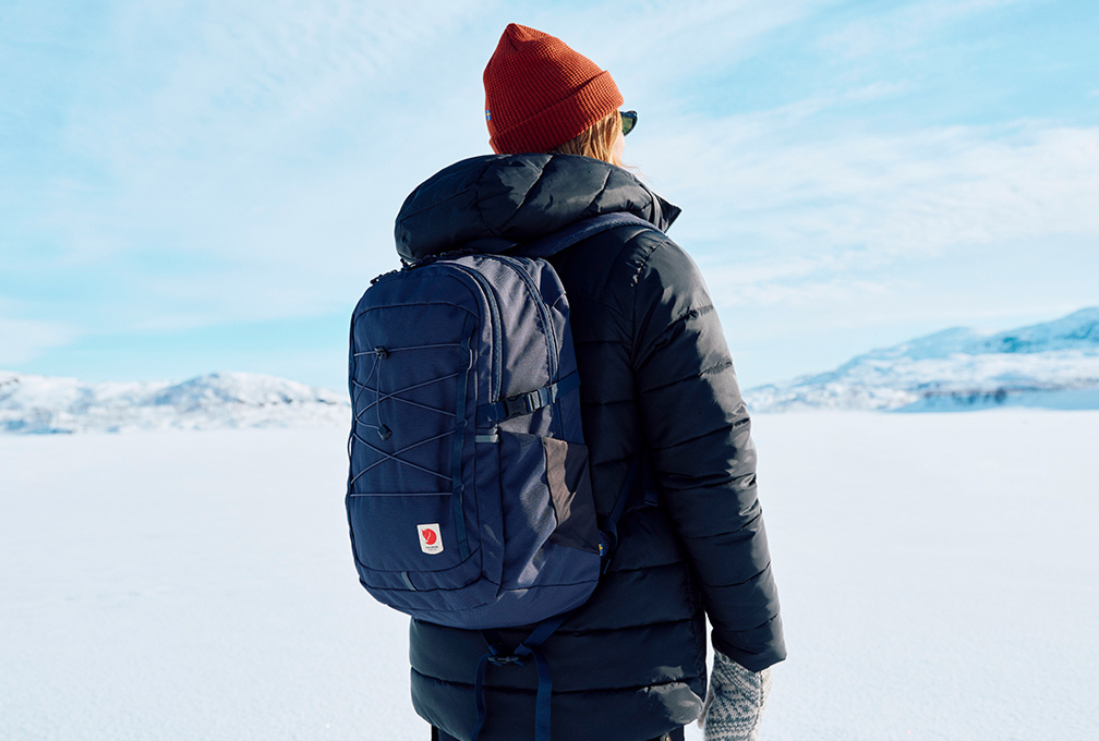 vrouw met dayback van fjallraven staat met dikke kleding aan in besneeuwd gebied