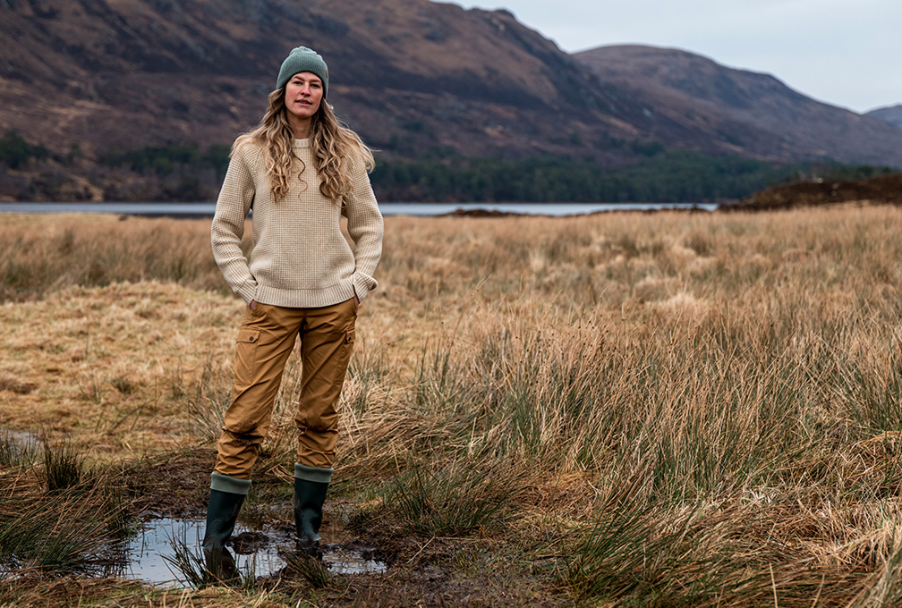vrouw in beige kleding met bergen en een meer op de achtergrond