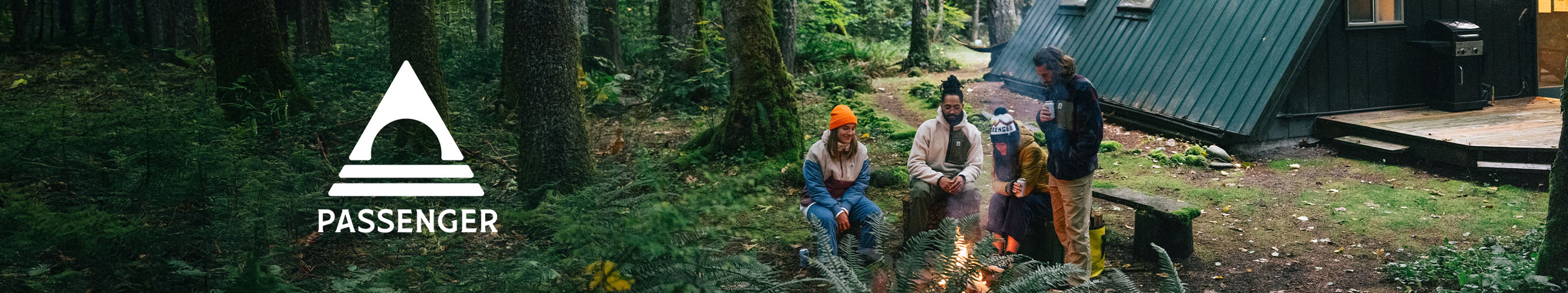 kampeerders in het bos bij kampvuur met huisje achter zich