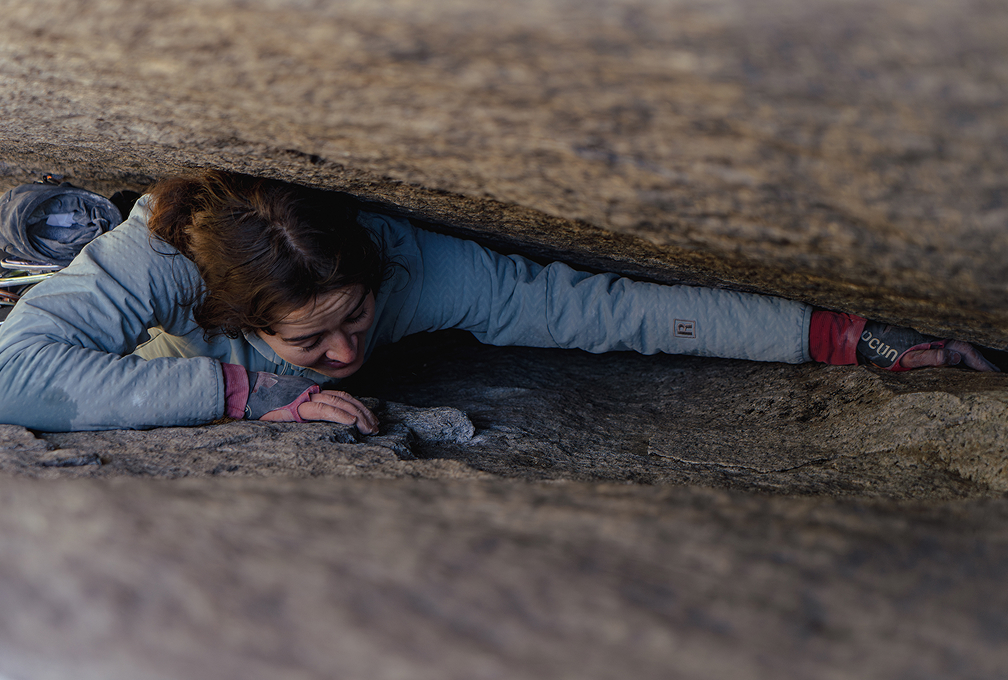 vrouw kruipt tussen een gleuf in de rotswand