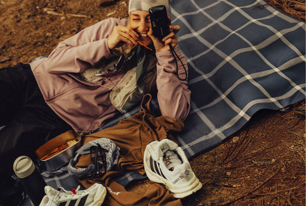 vrouw ligt op picknickkleed en fotografeert met oude camera