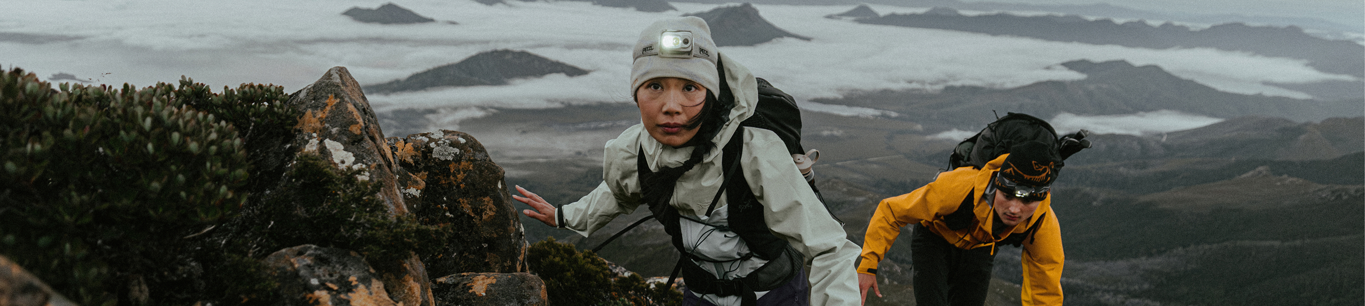 Twee wandelaars in Arc’teryx wandelkleding met rugzakken en hoofdlampen in de bergen