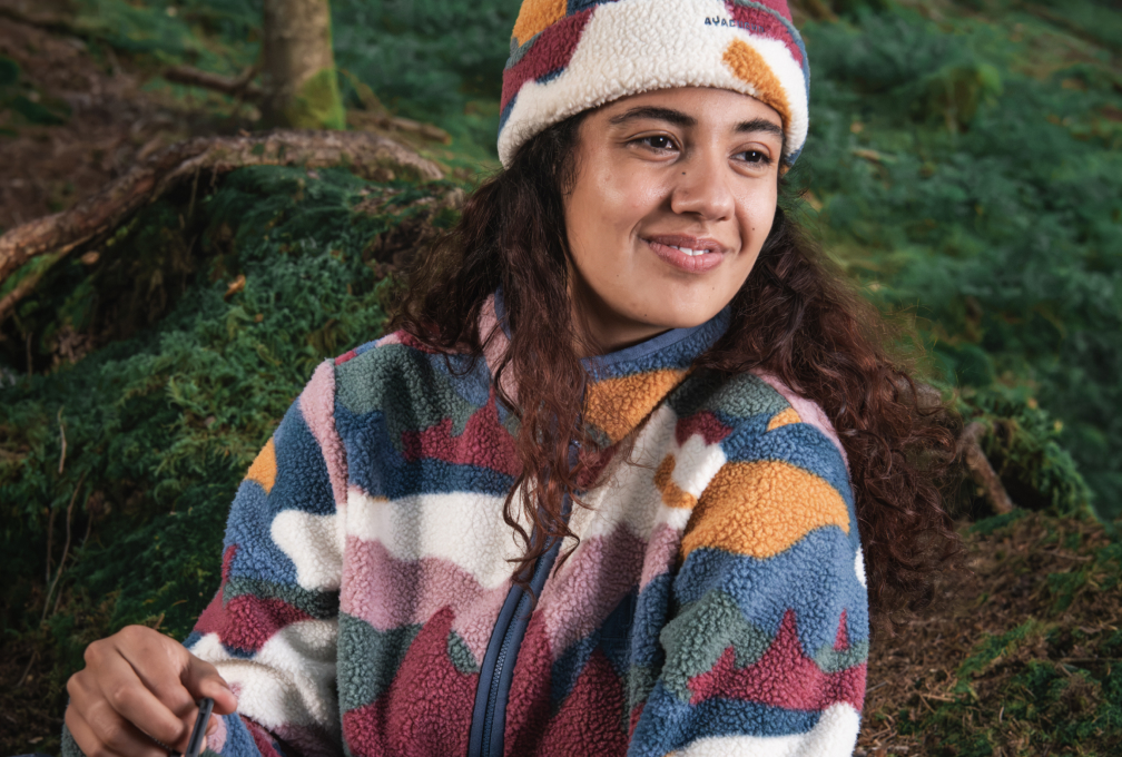 Vrouw in een bos met een kleurrijke Ayacucho-fleece en bijpassende gebreide muts.