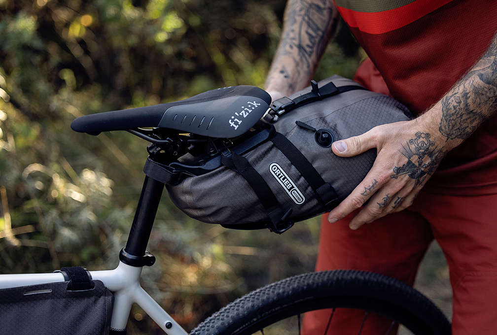 Grijze Ortlieb zadeltas onder het zadel van een mountainbike
