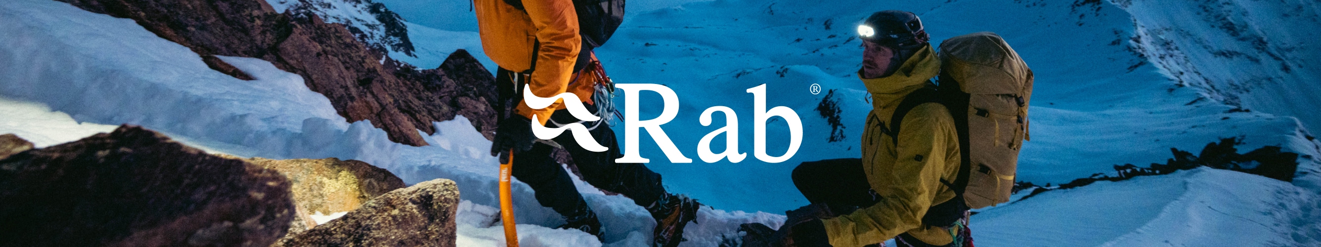 Twee bergsporters met Rab jassen, rugzakken en hoofdlampen tijdens een tocht door de sneeuw