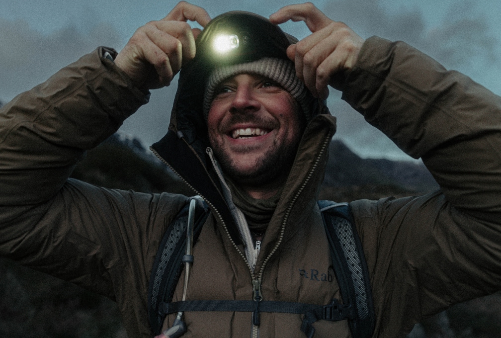 Man in een Rab outdoorjas met hoofdlamp in de bergen
