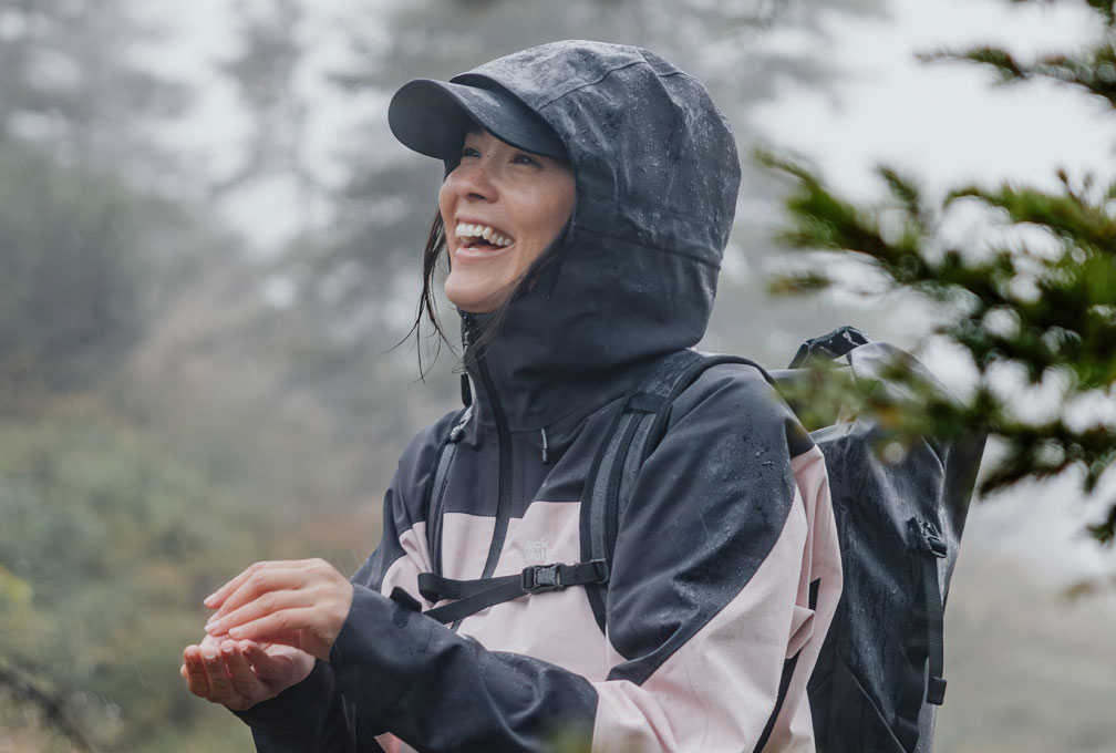 vrouw wandelt door de bergen in regenkleding